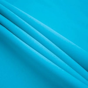 May include: A close-up of a smooth, bright blue fabric with soft folds and wrinkles.