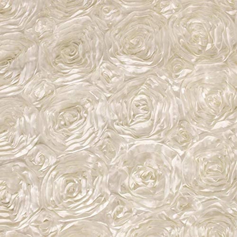 May include: A close-up of a white satin fabric with a rosette pattern. The fabric is soft and luxurious, and the rosettes are arranged in a random pattern.