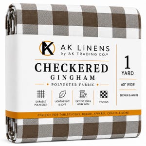 May include: A folded bolt of brown and white checkered gingham polyester fabric with a paper label reading AK LINENS, CHECKERED GINGHAM, 1 YARD, 60 INCHES WIDE, and icons for durable, lightweight, easy to sew, and 1 inch check pattern.