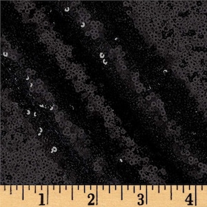 May include: Black sequined fabric with a slight sheen. The fabric is measured in inches on a ruler.