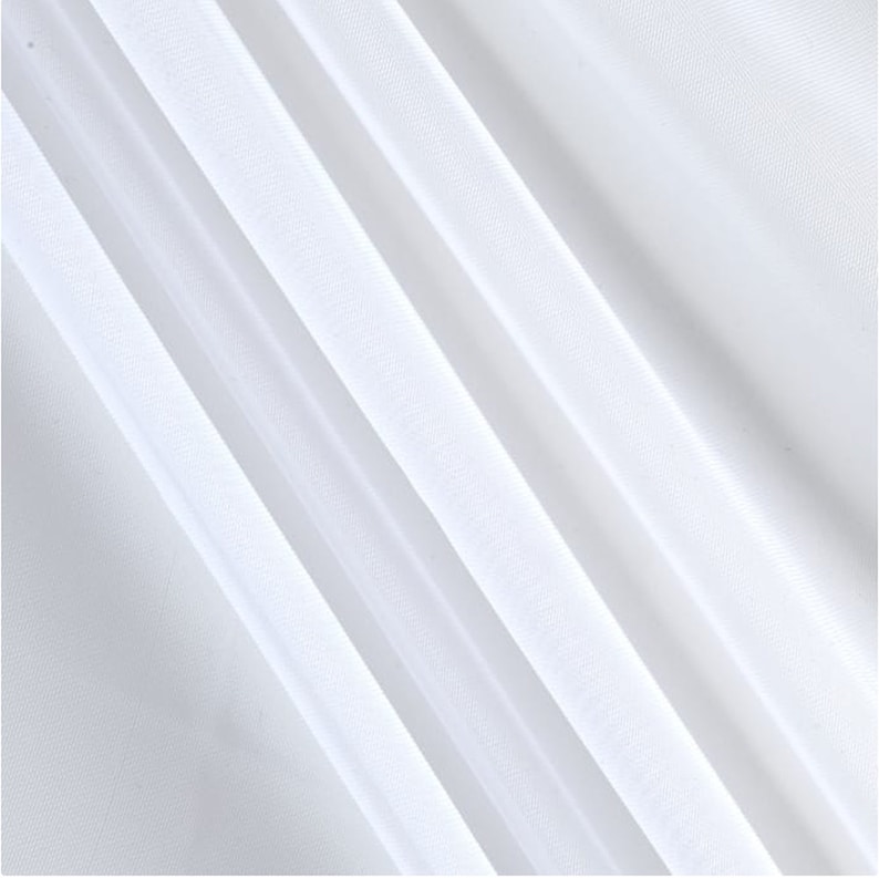 Puede incluir: Tela blanca transparente con una textura suave y sedosa. La tela est&aacute; doblada en diagonal, creando l&iacute;neas suaves y fluidas.