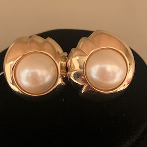 Signed Les Bernard gold clip earrings with cream center pearl and a wave design around the pearl.