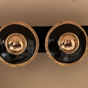 Vintage black enamel and shiny gold tone round dimensional clip on earrings with gold rims.