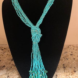 Long sterling silver turquoise multi-strand knotted tassel necklace with interspersed clear beads and lobster closure.