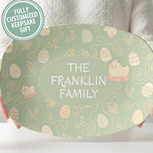 May include: Oval-shaped, light green platter with an Easter theme. The platter features a repeating pattern of Easter eggs, chicks, and floral elements. The center oval displays "THE FRANKLIN FAMILY" in white. A circular sticker reads "FULLY CUSTOMIZED KEEPSAKE GIFT".
