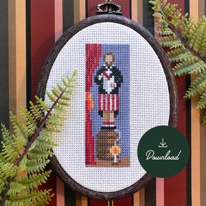 Peut inclure: Modèle de point de croix d'une personne debout sur un tonneau avec un rideau rouge derrière elle. La personne porte une veste bleue, une chemise blanche, un pantalon rayé rouge et blanc et des chaussures noires. Le motif est dans un cadre ovale blanc avec une bordure en bois brun.