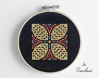 May include: A black embroidery hoop with a yellow, red, and blue geometric pattern stitched on black fabric. The pattern is a stylized flower with four petals.