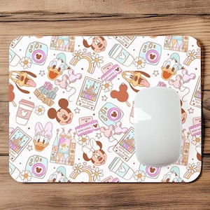 May include: A rectangular mousepad with a white background and a repeating pattern of cartoon characters, cameras, coffee cups, and rainbows. The mousepad has a white mouse on it. The design includes Mickey and Minnie Mouse, Donald Duck, and Daisy Duck.