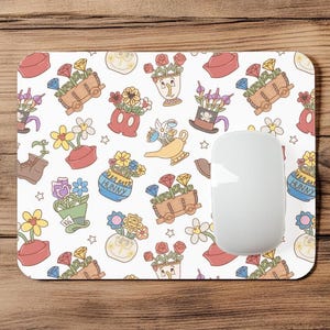 May include: White rectangular mousepad with a colorful pattern of cartoon flowers, gems, and various containers. A white computer mouse is on the right side of the pad. The design includes a Mickey Mouse head, a Hunny pot, and a genie lamp.