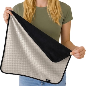 May include: A rectangular mat featuring a light beige grid pattern on one side and a solid black fabric on the reverse. The mat has rounded corners, a black border trim, and a small black label with the text RADHALT visible on the bottom edge.