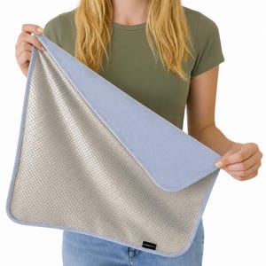 May include: A rectangular mat featuring a metallic silver grid pattern on one side and a solid light blue fabric on the reverse. The mat has rounded corners and a small black rectangular tag with white text reading RADHALT on the bottom edge.