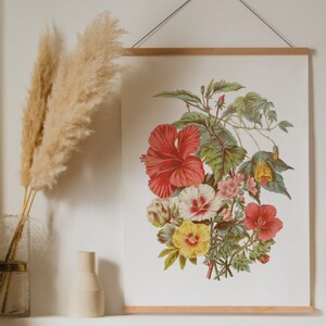 May include: A botanical print featuring a vibrant bouquet of hibiscus and other flowers in shades of red, yellow, and pink, with green foliage. The artwork is displayed on a white background and framed with a wooden hanger.