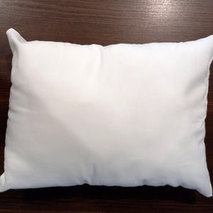 May include: A plain white pillow with a smooth surface. The pillow is rectangular and has a seam down the centre.