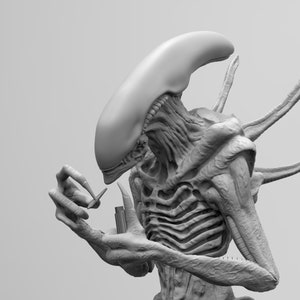Puede incluir: Un modelo 3D impreso en gris detallado de una criatura extraterrestre con una cabeza larga y delgada y un cuerpo segmentado. La criatura tiene cuatro dedos largos y delgados en cada mano y sostiene un pequeño objeto rectangular en su mano derecha.