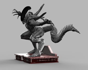 Puede incluir: Una figura de alien gris con una cola larga y segmentada, de pie sobre una base roja y gris. El alien está en posición de cuclillas con los brazos levantados.