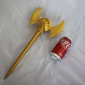 May include: A gold-colored staff with a winged eye design at the top. The staff is about the size of a soda can.