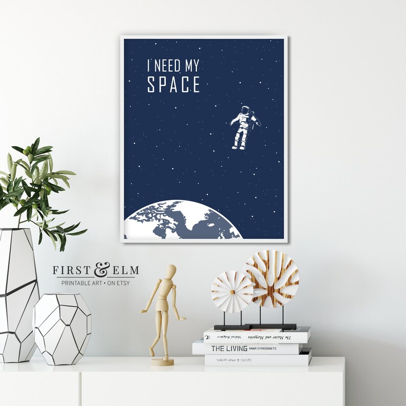 May include: A printable poster with a blue background and white text that reads "I need my space". An astronaut floats in space above a white globe with a blue outline. The poster is framed in white.