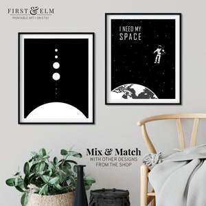 May include: Two black and white printable art prints with space themes. The first print features a stylised image of a planet with a ring and several smaller planets. The second print features an astronaut floating in space above the Earth with the text "I need my space".