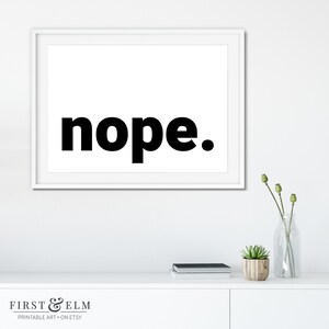 May include: A black and white printable art print with the word "nope" in bold, black font. The print is framed in a white frame and is hanging on a white wall.