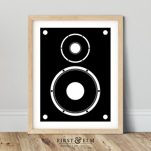 Pu&ograve; includere: Illustrazione in bianco e nero di un altoparlante con due grandi altoparlanti rotondi. L'altoparlante &egrave; incorniciato in una cornice di legno chiaro.