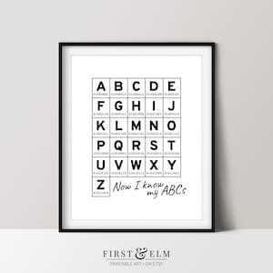 Può includere: Stampa d'arte stampabile in bianco e nero con l'alfabeto in un formato a griglia. Ogni lettera è circondata da un quadrato nero con un codice binario sottostante. Il testo "Now I know my ABCs" è sotto la griglia.