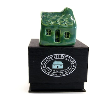 Può includere: Una piccola casa in ceramica verde con tetto in tegole, seduta su una scatola nera con il testo "Glenshee Pottery, Home of the Wee Bothy, Hand Made in Scotland".