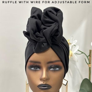 May include: Black turban with a ruffle detail on top. The turban is made of a soft, stretchy fabric and has a wire inside to help it hold its shape.
