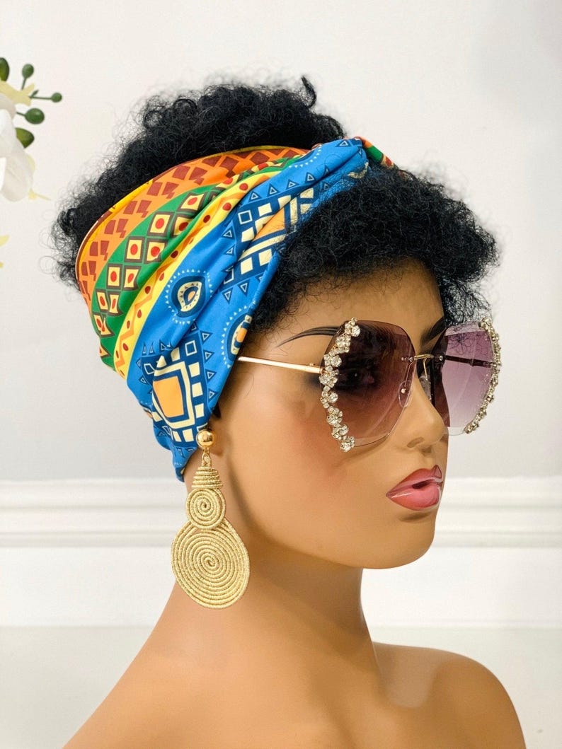 May include: A woman wearing a blue, yellow, orange, and green patterned head wrap, large gold hoop earrings, and clear sunglasses with rhinestones.