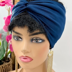 May include: A navy blue turban headband made of soft fabric. The headband is twisted and knotted at the top, creating a stylish and comfortable look.