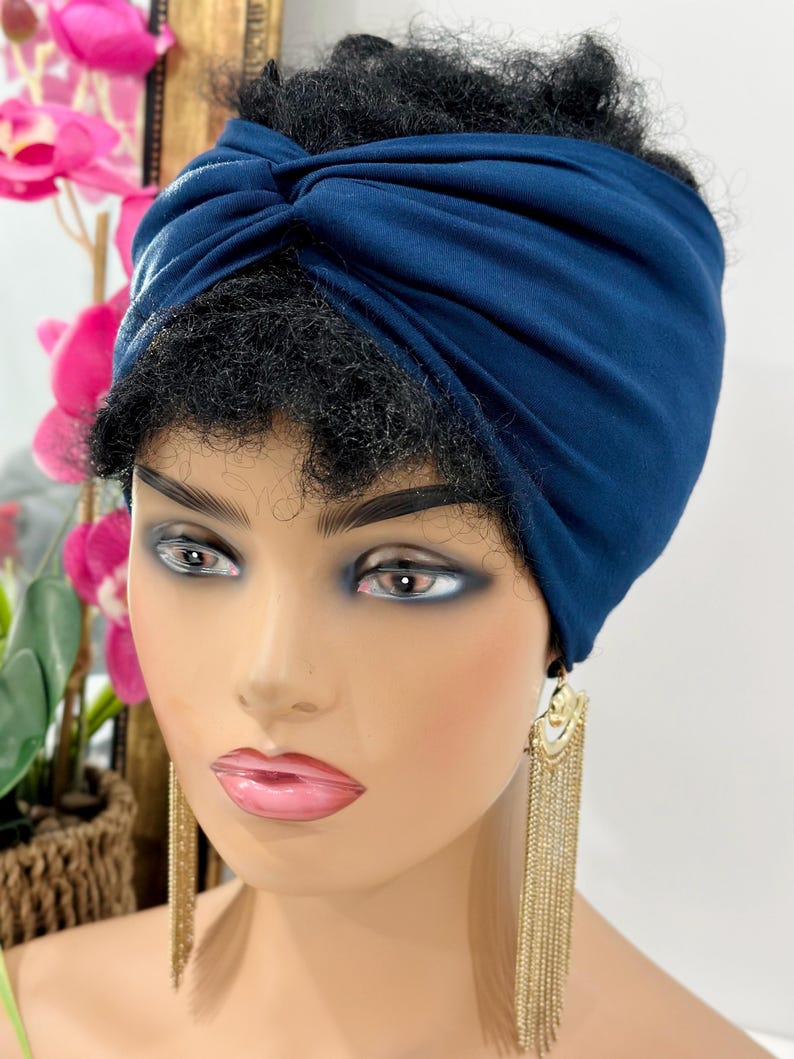 May include: A navy blue turban headband made of soft fabric. The headband is twisted and knotted at the top, creating a stylish and comfortable look.