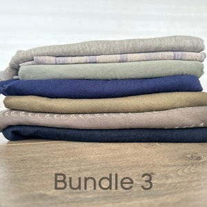 May include: A stack of seven folded fabric pieces in various colors, including gray, blue, green, and brown. The fabric pieces are arranged in a neat pile. The text "Bundle 3" is written below the pile of fabric.
