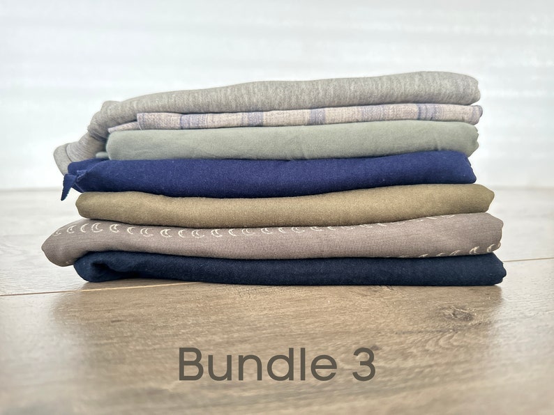 May include: A stack of seven folded fabric pieces in various colors, including gray, blue, green, and brown. The fabric pieces are arranged in a neat pile. The text "Bundle 3" is written below the pile of fabric.