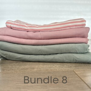 May include: A stack of four fabric squares in pink and green colors. The top square is pink and white striped. The text "Bundle 8" is written on the wooden surface below the fabric.