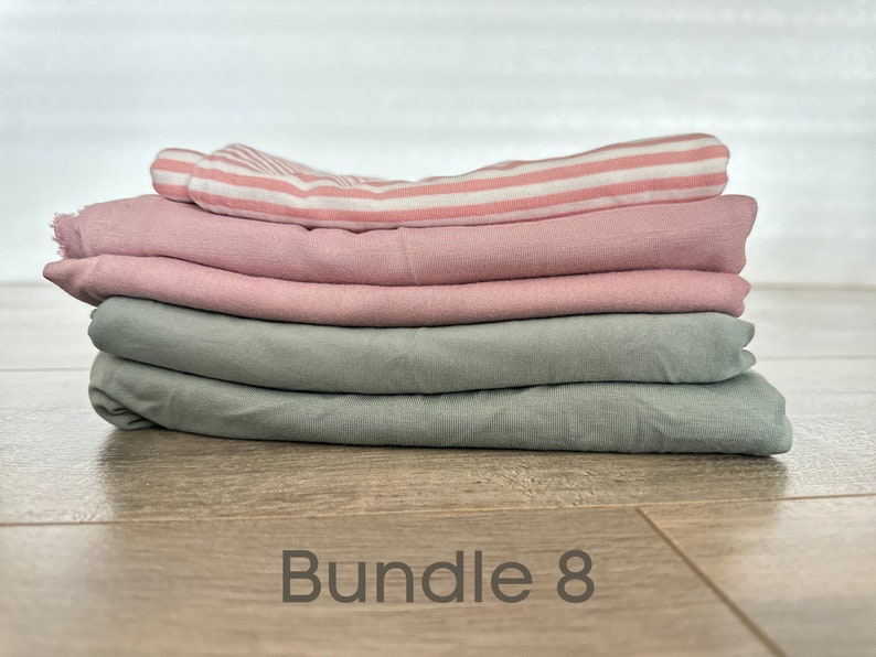 May include: A stack of four fabric squares in pink and green colors. The top square is pink and white striped. The text "Bundle 8" is written on the wooden surface below the fabric.