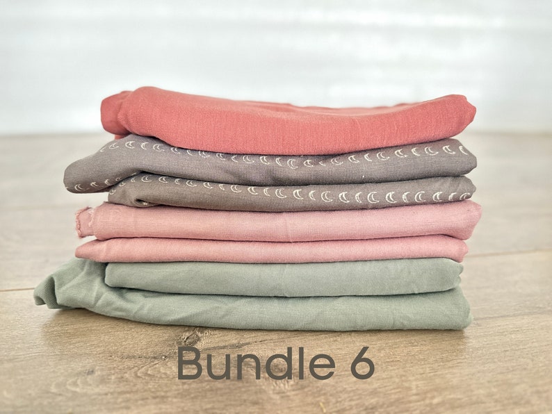 May include: A stack of six fabric squares in various shades of pink, green, and brown. The fabric squares have a subtle pattern of white crescent moons. The text "Bundle 6" is printed below the stack of fabric.