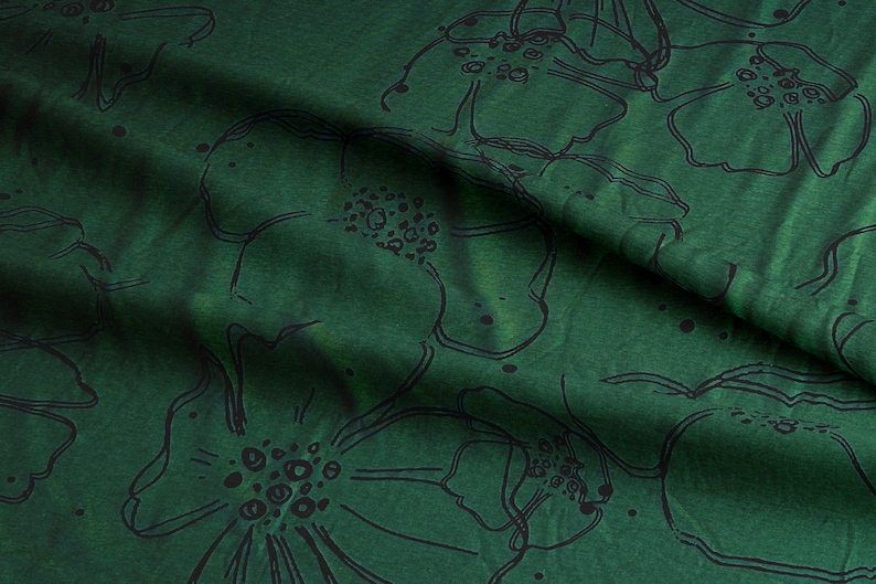 Puede incluir: Tela verde con un patr&oacute;n floral negro. La tela est&aacute; doblada y tiene una superficie texturizada.
