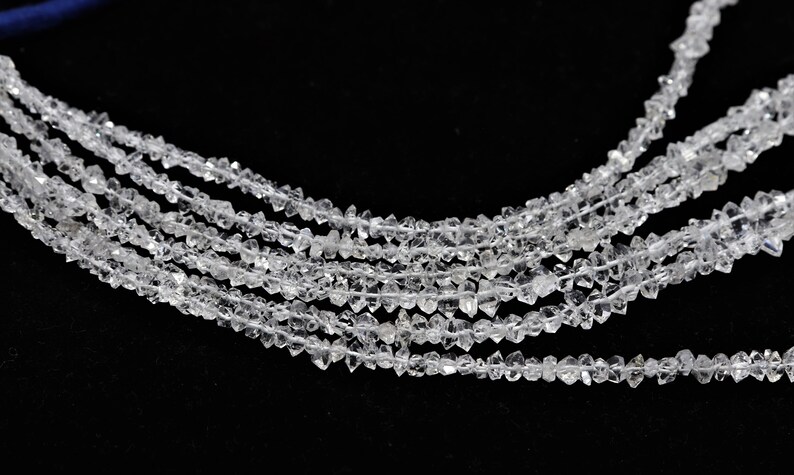 K&ouml;nnte beinhalten: Eine Str&auml;hne aus klaren, facettierten, diamantf&ouml;rmigen Perlen. Die Perlen sind auf einem durchsichtigen Faden aufgereiht und in einer Reihe angeordnet. Die Perlen sind alle gleich gro&szlig; und gleich geformt.