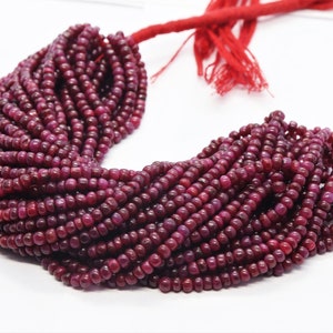 Puede incluir: Una hebra de cuentas de rubí rojo oscuro, cada cuenta es redonda y lisa. Las cuentas están enhebradas en un cordón rojo y están listas para ser utilizadas en la elaboración de joyas.