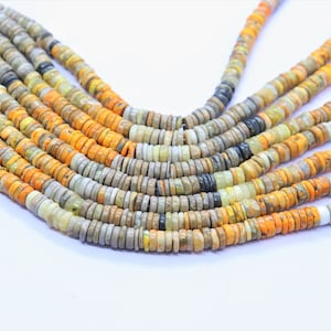 May include: A strand of multi-colored gemstone beads. The beads are round and flat, and they are arranged in a pattern of yellow, orange, gray, and black. The beads are strung on a clear thread.