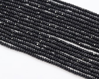 May include: A strand of black faceted gemstone beads. The beads are small and round, and they are strung on a clear thread.