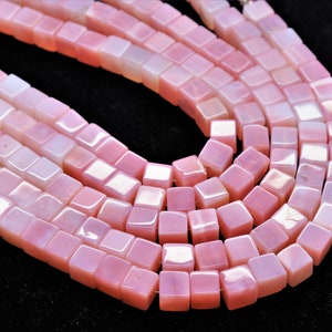 Puede incluir: Una hebra de cuentas cuadradas iridiscentes de color rosa. Las cuentas están hechas de piedra natural y tienen un acabado liso y pulido.