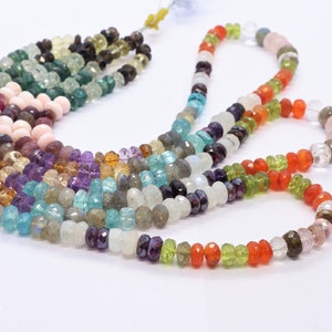 May include: A multi-strand necklace of gemstone beads in various colors, including pink, green, blue, purple, and orange. The beads are faceted and have a smooth, polished finish.