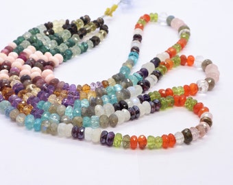 May include: A multi-strand necklace of gemstone beads in various colors, including pink, green, blue, purple, and orange. The beads are faceted and have a smooth, polished finish.