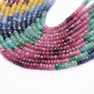 May include: A multi-strand necklace of faceted gemstone beads. The beads are in shades of pink, green, blue, and yellow. The necklace is arranged in a semi-circle shape.