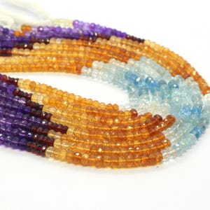 Può includere: Un filo di perle di pietre preziose in tonalità di viola, arancio e blu. Le perle sono sfaccettate e hanno una finitura liscia e lucida.
