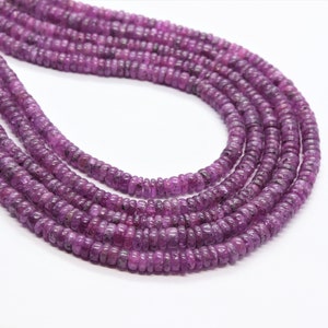 Puede incluir: Una hebra de cuentas de piedras preciosas de color púrpura, con un acabado liso y pulido. Las cuentas son redondas y tienen una forma ligeramente irregular. La hebra mide aproximadamente 46 cm de largo.