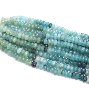 Op de afbeelding: Strengen aquamarijn edelsteen kralen. De kralen zijn een mix van licht- en donkerblauwgroene kleuren, met een afgeronde, tonvormige vorm. De kralen zijn geregen, klaar voor het maken van sieraden.