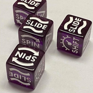 May include: Four translucent purple dice with white text and symbols. Each die features the word "SLIDE" and other action words like "SPIN" and "SHIFT". The dice are arranged on a white surface.