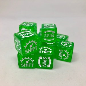 May include: A collection of translucent green dice with white text and symbols. Each die features the words "SHIFT" and "SPIN", along with a gear-like graphic. The dice are stacked and arranged, showcasing their unique design.