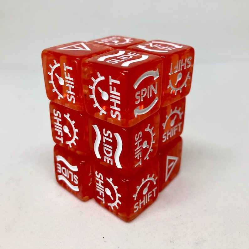 May include: A transparent red cube puzzle with white text and symbols. The text includes "SHIFT", "SLIDE", and "SPIN", along with gear and arrow icons. The cube is a brain teaser or a game.